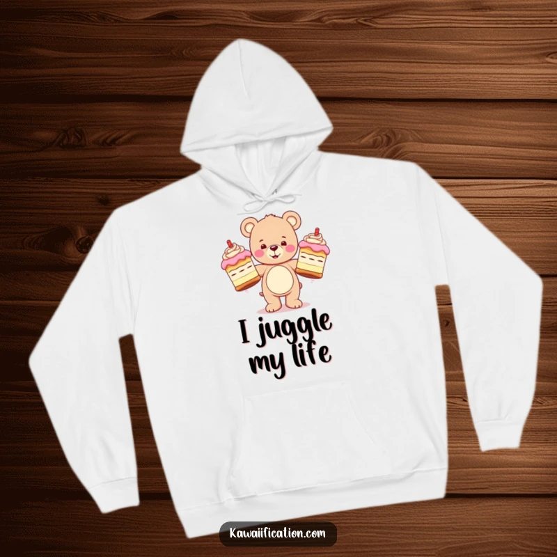 Funny hoodie depicting a happy teddy bear character juggling three oversized, wobbly cakes, offering warmth and a touch of playful disorder.